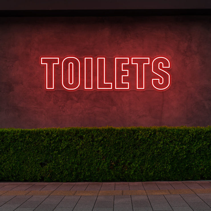 red toilets neon sign hanging on outdoor wall
