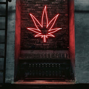 red weed leaf neon sign hanging on bar wall