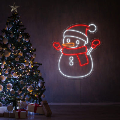 snowman neon sign hanging on wall next to christmas tree