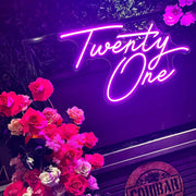 pink twenty one neon sign hanging on black frame with flowers