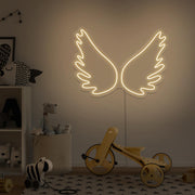 warm white angel wings neon sign hanging on kids bedroom wall