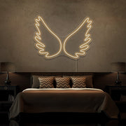 warm white angel wings neon sign hanging on bedroom wall