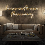warm white dreams worth more than money neon sign hanging on living room wall