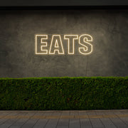warm white eats neon sign hanging on outside wall