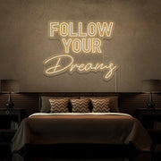 warm white follow your dreams neon sign hanging on bedroom wall