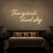 warm white the grind dont stop neon sign hanging on bedroom wall