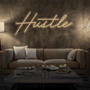 warm white hustle neon sign hanging on living room wall