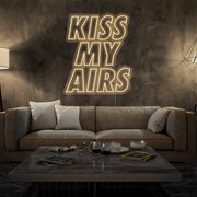 warm white kiss my airs neon sign hanging on living room wall