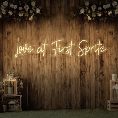 warm white love at first spritz neon sign hanging on timber wall