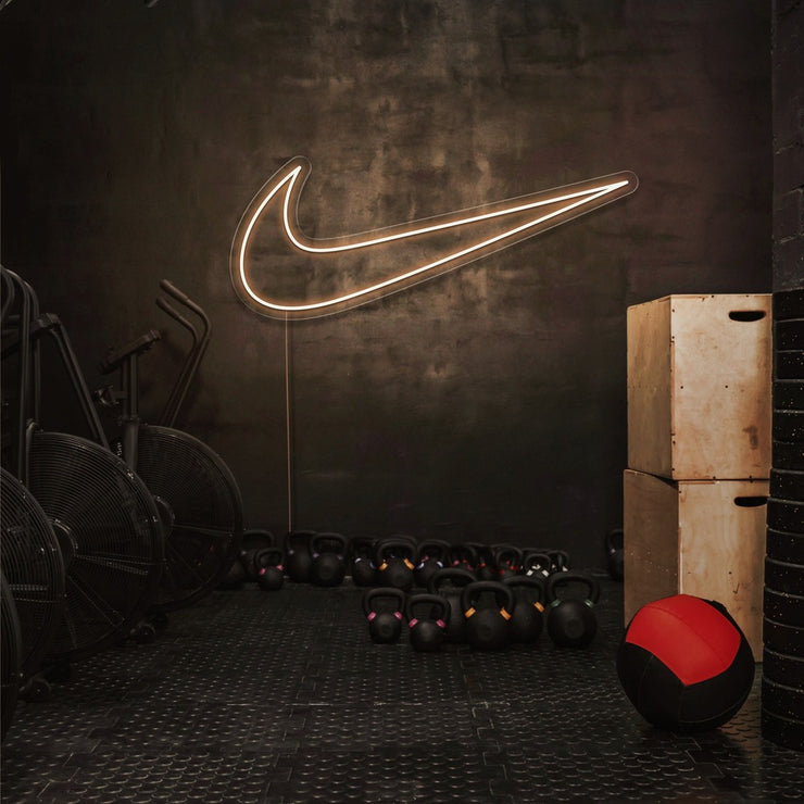 warm white nike swoosh neon sign hanging on gym wall