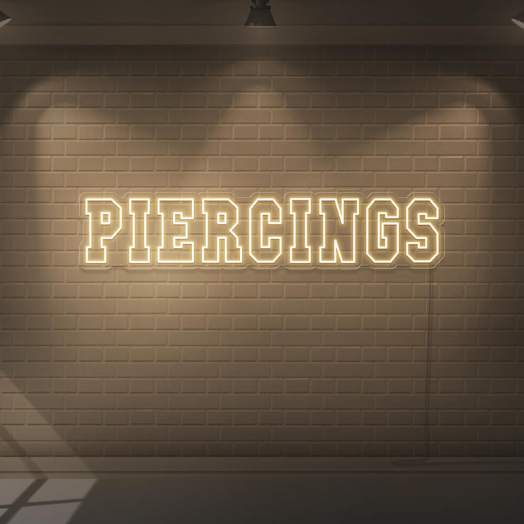 warm white piercings neon sign hanging on wall