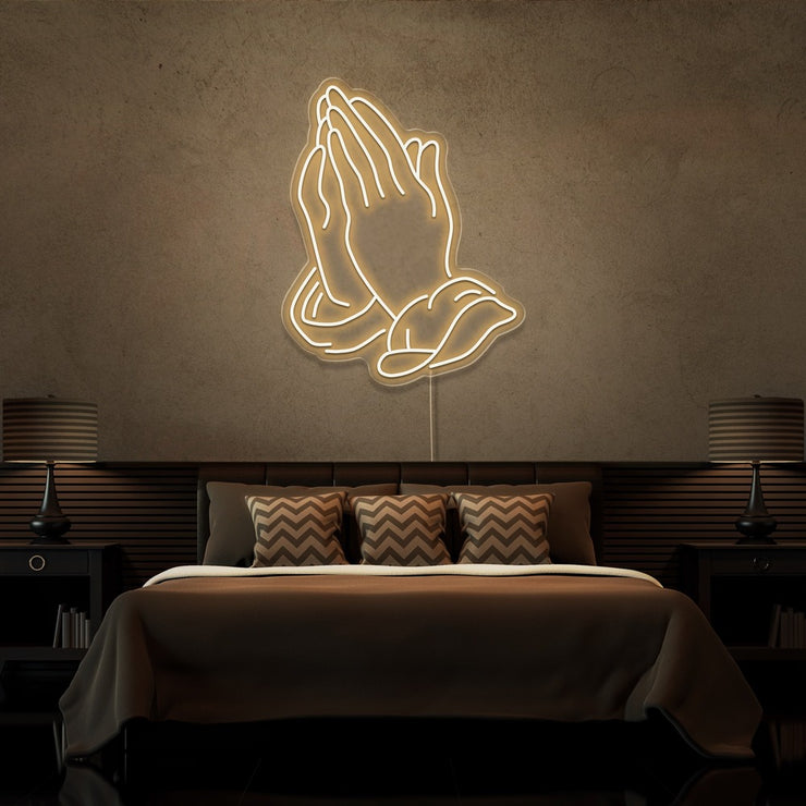 warm white praying hands neon sign hanging on bedroom wall