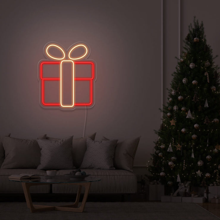 warm white Christmas present neon sign hanging on lounge room wall next to Christmas tree