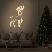 warm white reindeer neon sign on hanging on living room wall next to christmas tree
