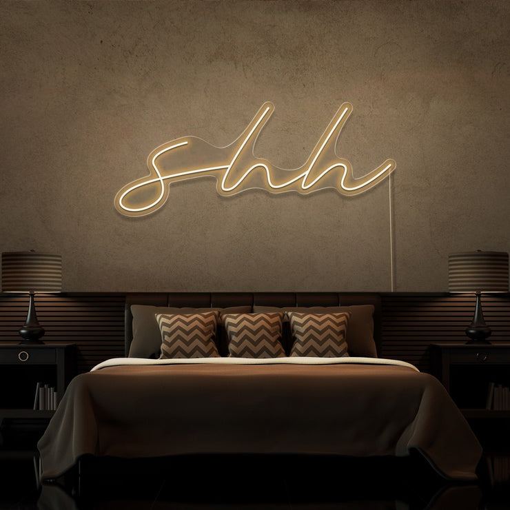 warm white shh neon sign hanging on bedroom wall