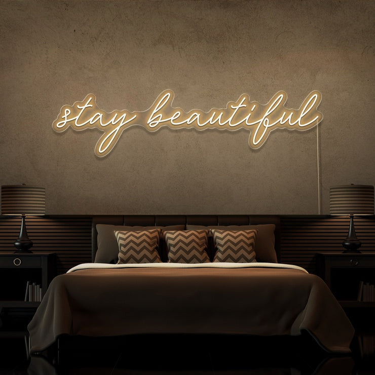 warm white stay beautiful neon sign hanging on bedroom wall