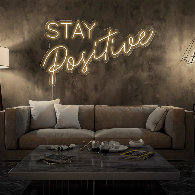 warm white stay positive neon sign hanging on living room wall