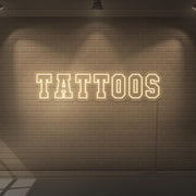 warm white tattoos neon sign hanging on wall
