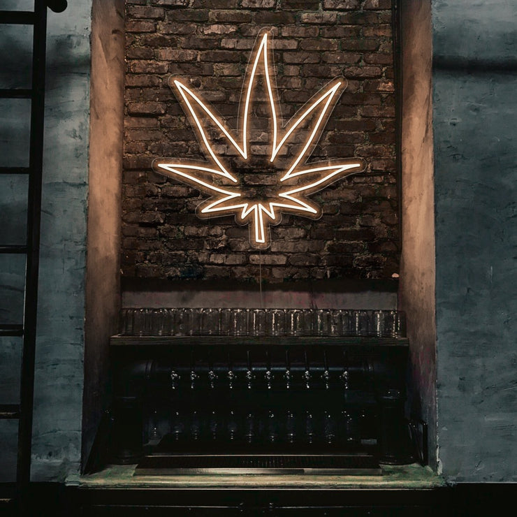 warm white weed leaf neon sign hanging on bar wall