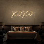 warm white xoxo neon sign hanging on bedroom wall