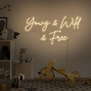warm white young wild and free neon sign hanging on kids bedroom wall