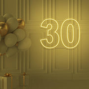 yellow 30 neon sign hanging on wall with balloons