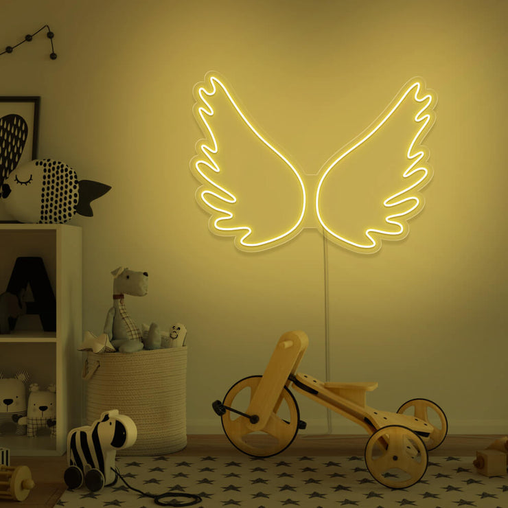 yellow angel wings neon sign hanging on kids bedroom wall