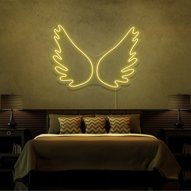yellow angel wings neon sign hanging on bedroom wall