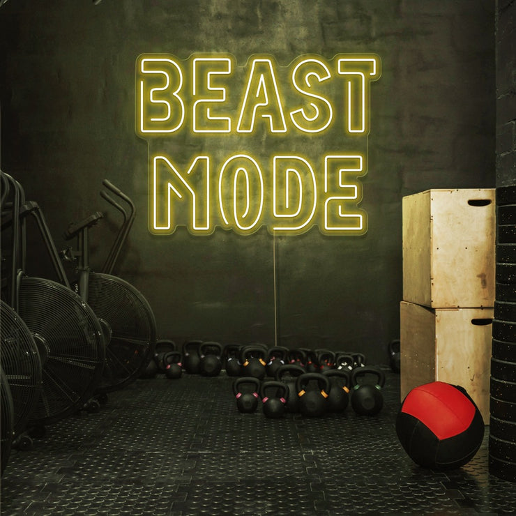 yellow beast mode neon sign hanging on gym wall