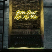 yellow bitch don't kill my vibe neon sign hanging on bar wall