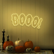 yellow boo neon sign with halloween pumpkins on floor
