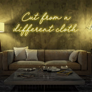 yellow cut from a different cloth neon sign hanging on living room wall