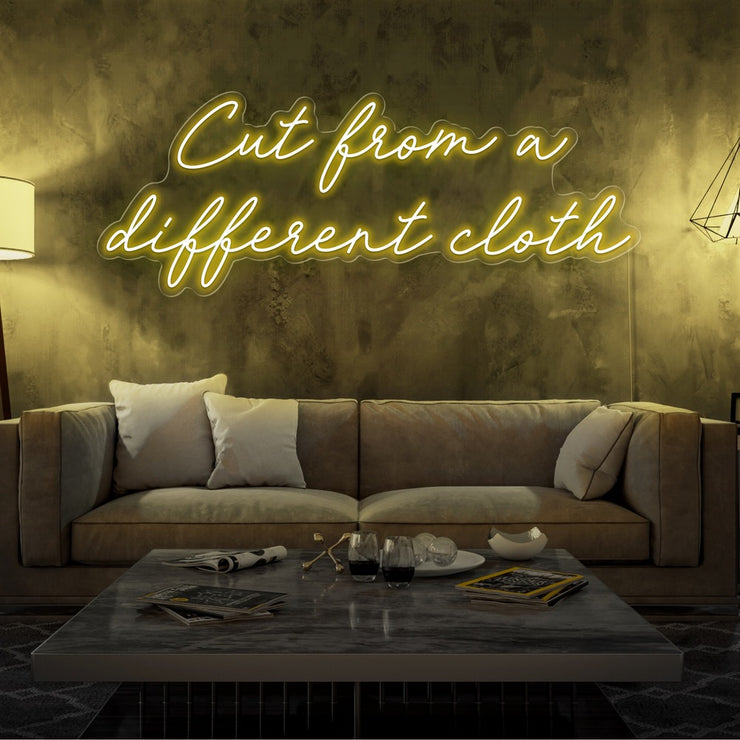 yellow cut from a different cloth neon sign hanging on living room wall