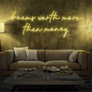 yellow dreams worth more than money neon sign hanging on living room wall