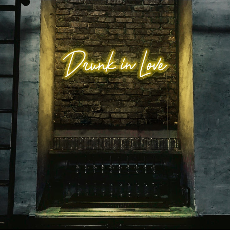 yellow drunk in love neon sign hanging on bar wall