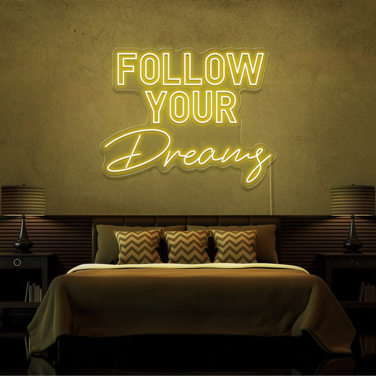 yellow follow your dreams neon sign hanging on bedroom wall