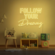 yellow follow your dreams neon sign hanging on kids bedroom wall