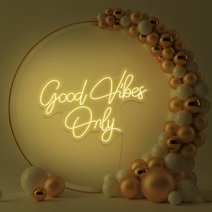 yellow good vibes only neon sign hanging inside balloon hoop backdrop