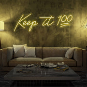 yellow keep it 100 neon sign hanging on living room wall
