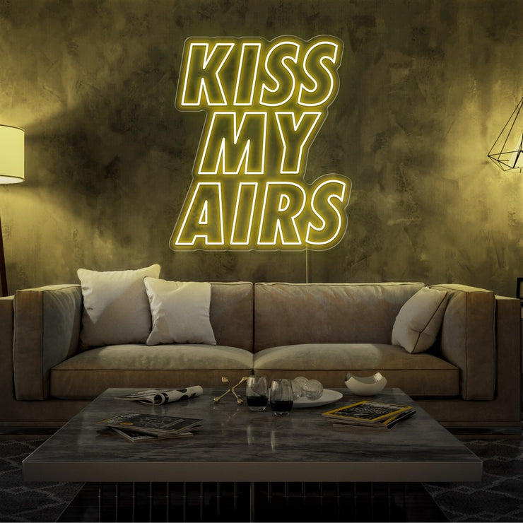 yellow kiss my airs neon sign hanging on living room wall