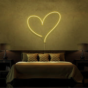 yellow pink love heart neon sign hanging on bedroom wall