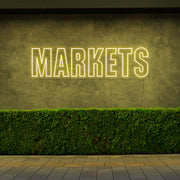 yellow markets neon sign hanging on outside wall