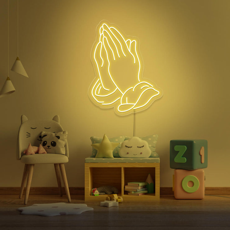 yellow praying hands neon sign hanging on kids bedroom wall