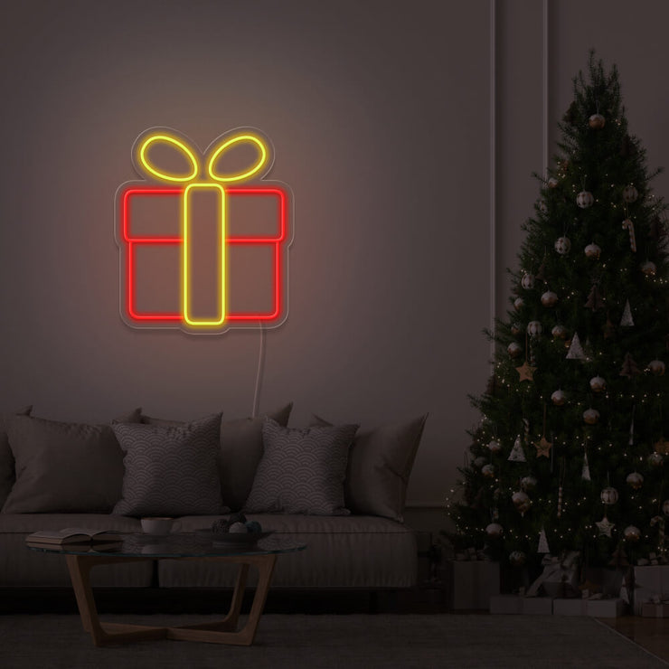 yellow Christmas present neon sign hanging on lounge room wall next to Christmas tree