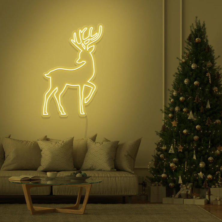 yellow reindeer neon sign hanging on living room wall next to christmas tree