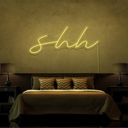 yellow shh neon sign hanging on bedroom wall