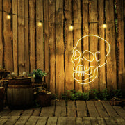 yellow skull neon sign hanging on timber fence