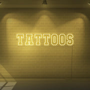 yellow tattoos neon sign hanging on wall