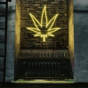 yellow weed leaf neon sign hanging on bar wall