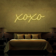 yellow xoxo neon sign hanging on bedroom wall